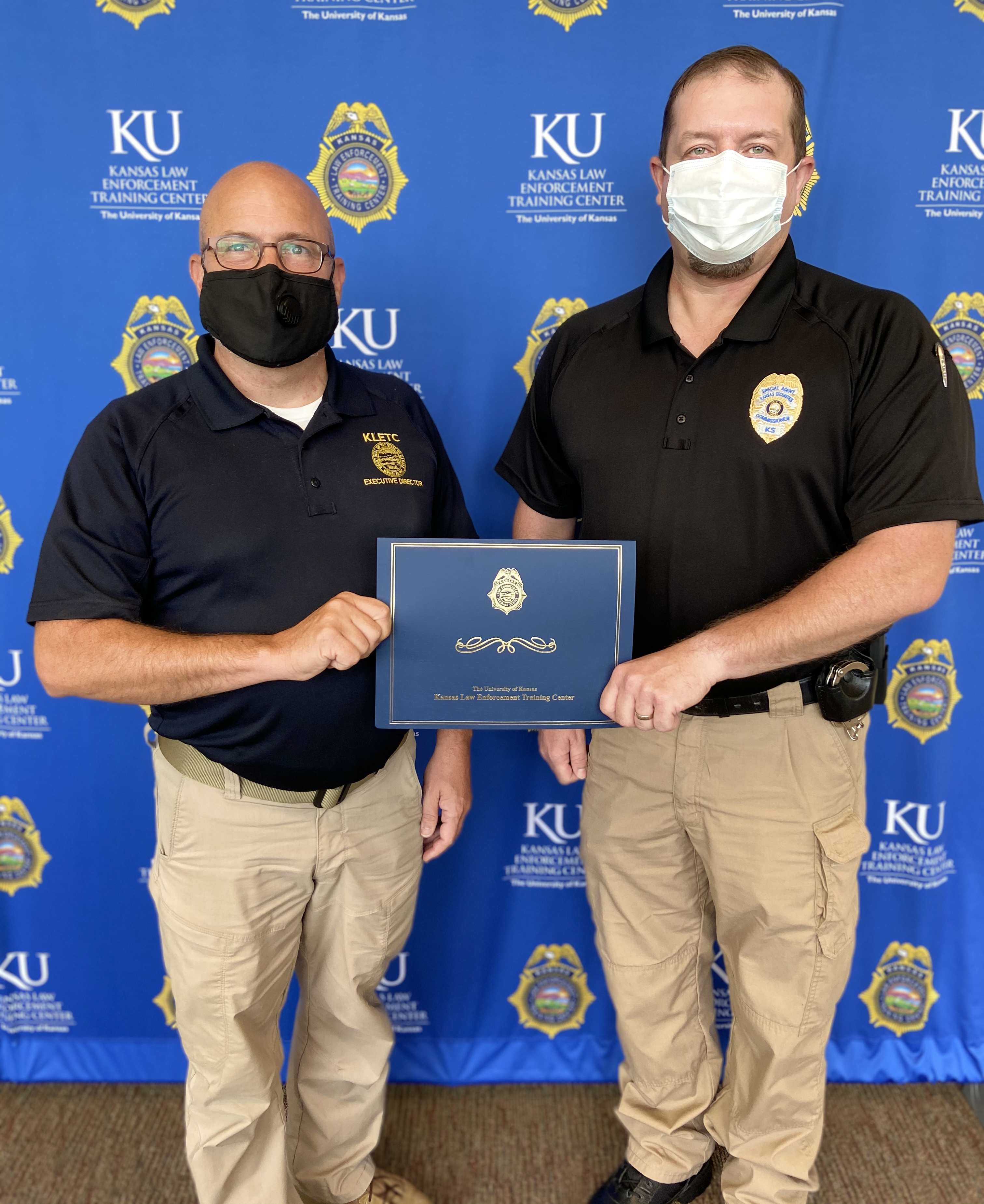 Ryan Morton, Special Agent with the Kansas Securities Commission, poses with his certificate with KLETC Executive Director Darin Beck.